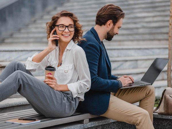 zwei Kollegen lehnen draußen Rücken an Rücken, Telefonat, Arbeit