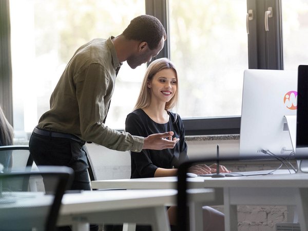 Two people, looking at PC, explanatory gesture